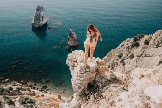 Woman travel sea. Happy tourist taking picture outdoors for memories. Woman traveler looks at the edge of the cliff on the sea bay of mountains, sharing travel adventure journey.