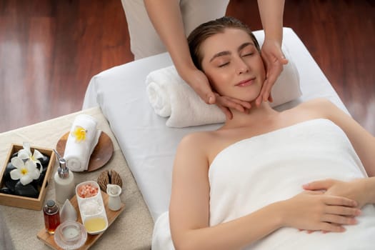 Caucasian woman enjoying relaxing anti-stress head massage and pampering facial beauty skin recreation leisure in dayspa modern light ambient at luxury resort or hotel spa salon. Quiescent