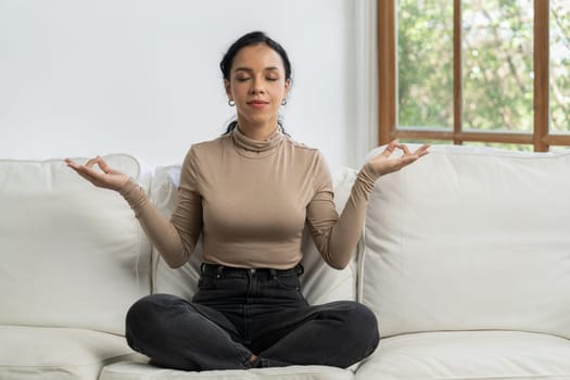 Young African American woman practice crucial mindful meditation at home living room for improving mental health strength and peaceful beautiful living