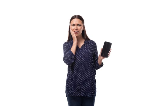 young sad brunette business woman dressed in a blue shirt shows a smartphone with a mockup.