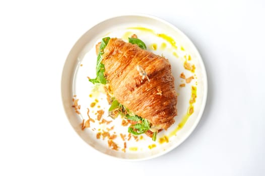 Croissant sandwich with ham, cheese and vegetables in white plate. Top view with copy space on white table