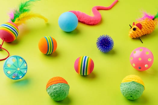 Colorful pet toys balls on green background close up