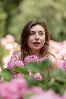 Hydrangeas Happy woman in pink dress amid hydrangeas. Large pink hydrangea caps surround woman. Sunny outdoor setting. Showcasing happy woman amid hydrangea bloom