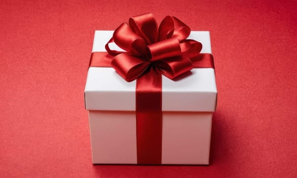 A beautifully wrapped gift adorned with a vibrant red bow sits elegantly against a backdrop of more presents and festive decorations. The scene captures the spirit of giving and the joy of the holiday season.