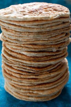 Flatbread lavash, chapati, naan, heap of tortilla on a blue background Homemade flatbread stacked