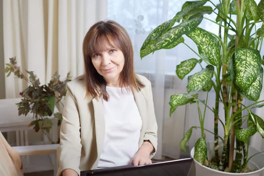 Elderly lady with a laptop in the room. A businesswoman is a leader, a manager is working. Grandma communicates with her grandchildren on the Internet