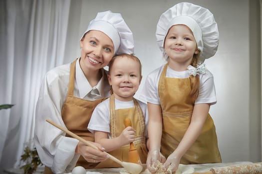 Cute oriental family with mother, daughter, son cooking in kitchen on Ramadan, Kurban-Bairam, Eid al-Adha. Funny family at a cook photo shoot. Pancakes, Maslenitsa, Easter