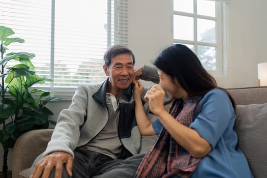 Older couples sit and chat and head over each other relaxed and happy on sofa at home on weekday in comfortable.