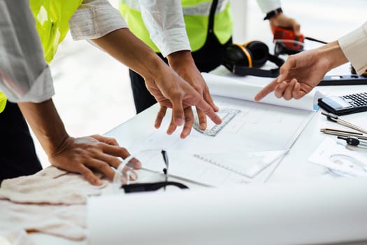 Team of engineers reviewing blueprints Sketch of a new construction project with engineering tools at office desk.