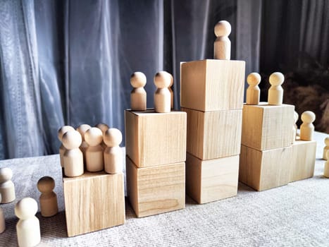 Wooden toy doll on high pedestal and many other figures below. Concept of leadership, which is not available to everyone. Victory and the winner. Talent, Recruitment employee and Successful business