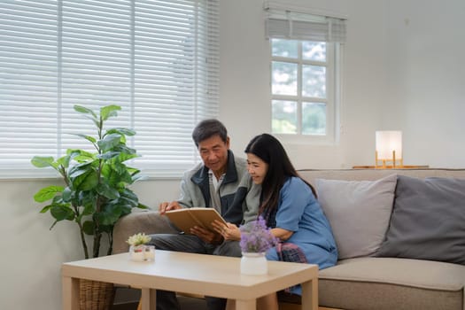 Retired elderly couple sits on couch in their home reading relaxing book. Senior Activity Concept.