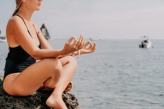 Woman sea yoga. Back view of free calm happy satisfied woman with long hair standing on top rock with yoga position against of sky by the sea. Healthy lifestyle outdoors in nature, fitness concept.