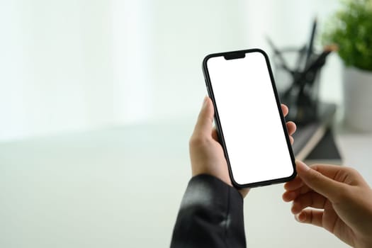 Businesswoman using smartphone at her working desk. Closeup, blank screen for advertising.