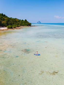 Asian woman at peddle board sup at Koh Kradan a tropical island in Thailand, Top down view picture of a woman paddling on the sup board.