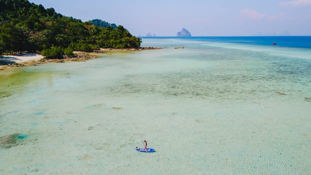 Asian woman at peddle board sup at Koh Kradan a tropical island in Thailand, Top down view picture of a woman paddling on the sup board.
