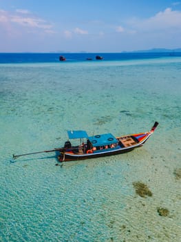 longtail boat in the turqouse colored ocean with clear water at Koh Kradan a tropical island in Trang Thailand, coral reef in front of a tropical island