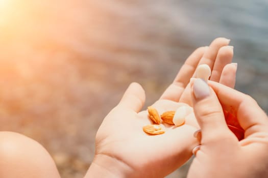 Woman eating milky almond nuts. A young caucasian woman choping fresh green almond after morning fitness yoga near sea. Only hands are visibly. Healthy vegan food. Slow motion. Close up