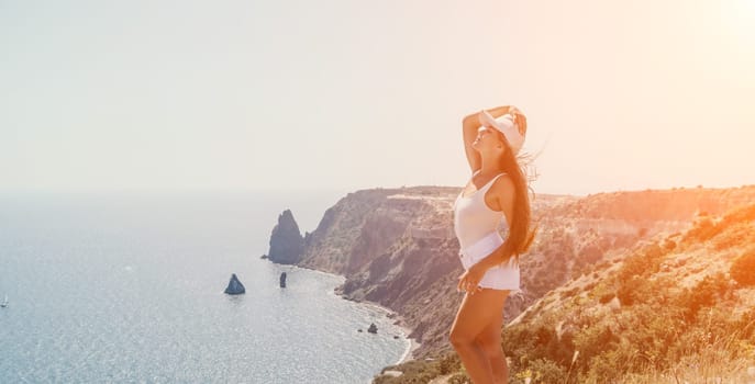 Woman travel sea. Young Happy woman in a long red dress posing on a beach near the sea on background of volcanic rocks, like in Iceland, sharing travel adventure journey