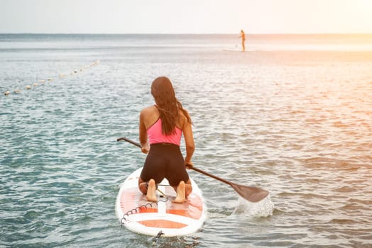 Sea woman sup. Silhouette of happy young woman in pink bikini, surfing on SUP board, confident paddling through water surface. Idyllic sunset. Active lifestyle at sea or river. Slow motion