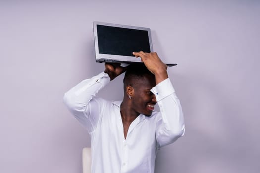 Optimistic african-american male student in a casual shirt using laptop pc isolated