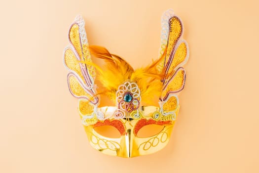 Happy Purim carnival decoration. Golden venetian ball mask isolated on pastel background with copy space, Jewish Purim or Mardi Gras in Hebrew, celebration holiday background banner design