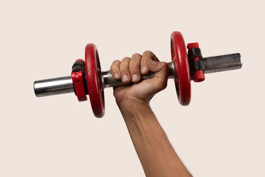 Male hand holding an old red dumbell on beige, isolated. High quality photo
