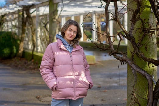 Young beautiful pretty tourist girl in warm hat and coat with backpack walking at cold autumn in Europe city enjoying her travel in Zurich Switzerland. Outdoor portrait of young tourist woman enjoying sightseeing