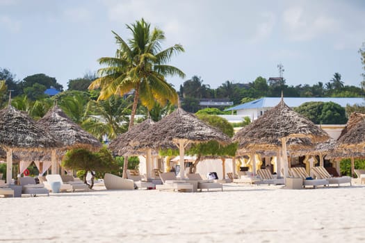 Wooden beach parasols and beach loungers.Luxury beach loungers and umbrella at luxurious beach resort. Summer beach concept,carefree, rest seaside,Nobody on the beach.