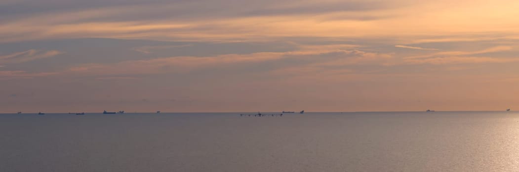 Panorama of dramatic sky at awesome sunset, flat sea at dawn, minimalist photo and mystery mood.