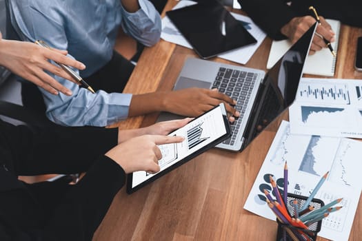 Multiracial analyst team use BI Fintech software to analyze financial data on meeting table. Financial dashboard data display on laptop screen with analyzed chart for marketing indication. Concord