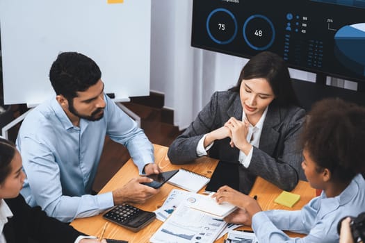 Top view multiracial analyst team use BI dashboard data to analyze financial report on meeting table. Group of diverse business people utilize data analysis by FIntech for business decision. Concord