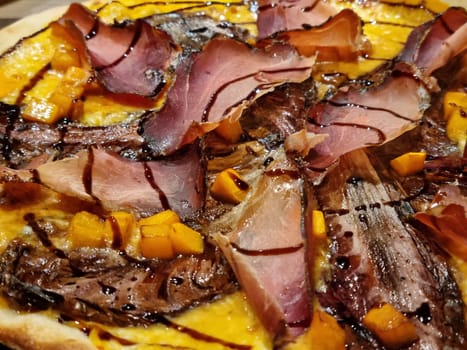 Close-up pizza with meat and vegetables on table.