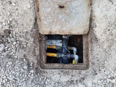 A gas meter in a hole with surrounding infrastructure.