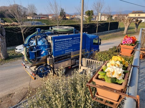 Vacuum truck parked next to flower pot on road