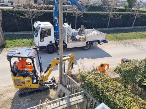 Excavator driving truck near asphalt road and trees