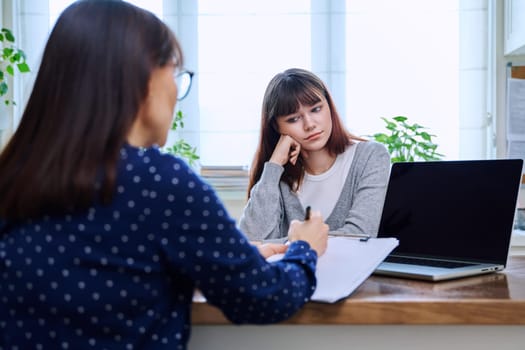 Teenage girl college student at therapy meeting with mental health professional social worker psychologist counselor sitting together in office. Psychology, psychotherapy, mental assistance support