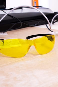 Engraver and yellow protection glasses on the desktop close up