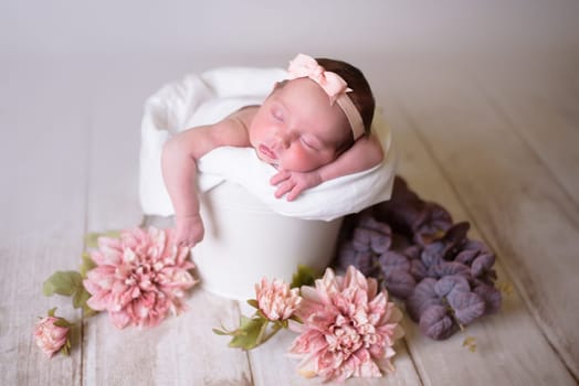 Tiny newborn girl in white cocoons on a white background. Professional studio photography.