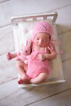 Tiny newborn girl in white cocoons on a white background. Professional studio photography.