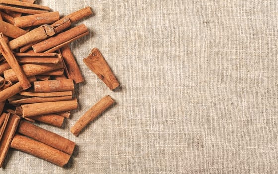 Top down view - Heap of cinnamon bark sticks on linen tablecloth, space for text on right side