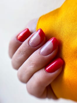 Woman hand with modern red French manicure over orange white background . High quality photo