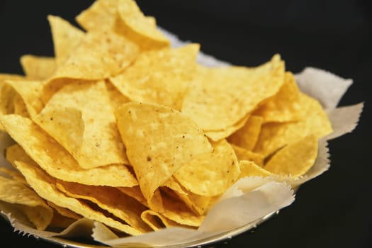 Crispy Tortilla Chips in Reflective Bowl Against Black Background, Perfect Snack for Mexican Cuisine