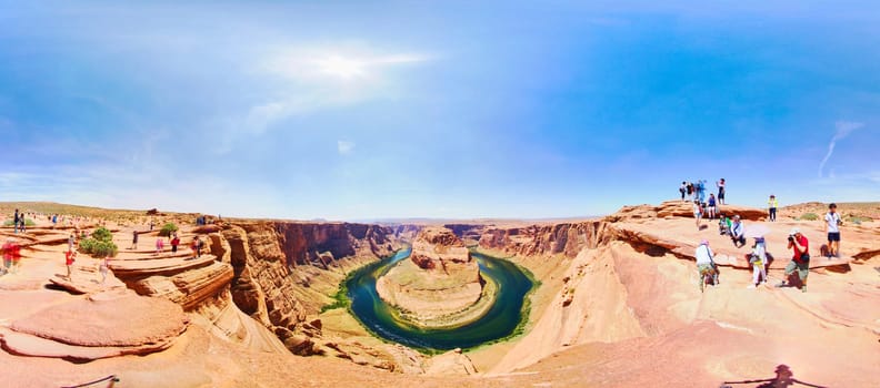Panoramic midday view of a horseshoe bend river flowing through vast Arizona canyon, Sedona, with casually dressed tourists exploring in 2016.