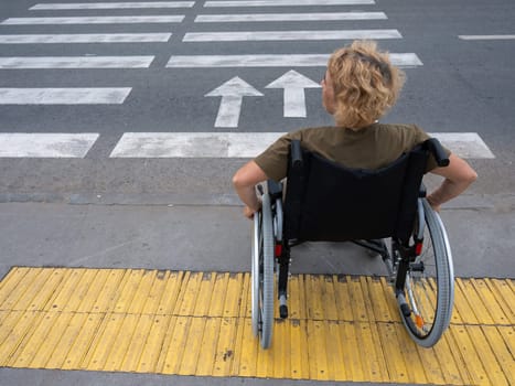 Rear view of an elderly woman on a wheelchair going to a pedestrian crossing