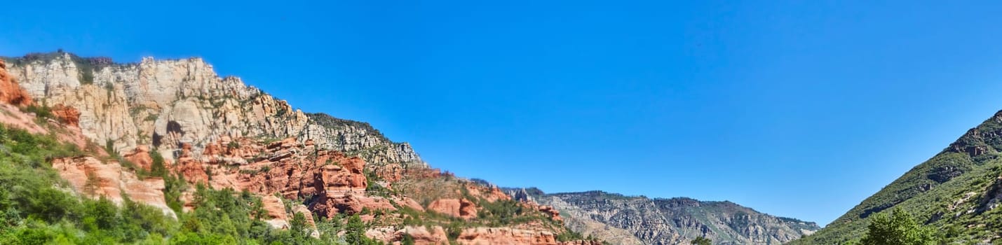 Panoramic view of vibrant Sedona mountain range under a clear blue sky, showcasing geological color stratification in 2016, Arizona