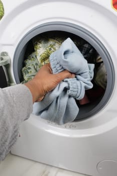 man putting shirt into washing machine