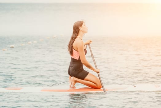 Close up shot of beautiful young caucasian woman with black hair and freckles looking at camera and smiling. Cute woman portrait in a pink bikini posing on a volcanic rock high above the sea