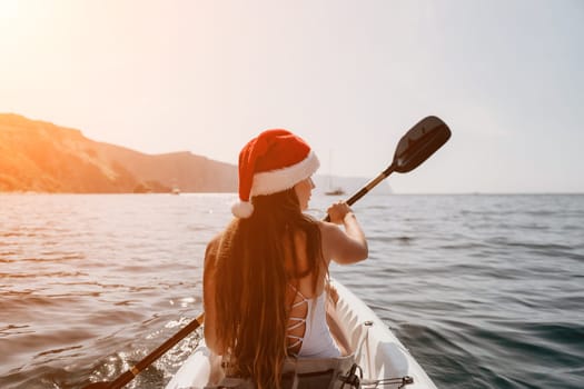 Woman in kayak back view. Happy young woman with long hair floating in transparent kayak on the crystal clear sea. Summer holiday vacation and cheerful female people relaxing having fun on the boat