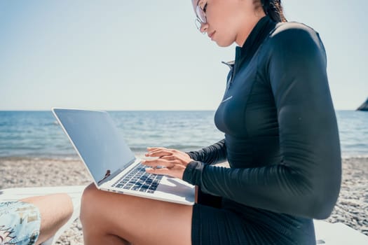 Digital nomad, Business man working on laptop by the sea. Man typing on computer by the sea at sunset, makes a business transaction online from a distance. Freelance, remote work on vacation