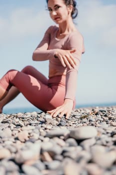 Young woman with long hair in white swimsuit and boho style braclets practicing outdoors on yoga mat by the sea on a sunset. Women's yoga fitness routine. Healthy lifestyle, harmony and meditation